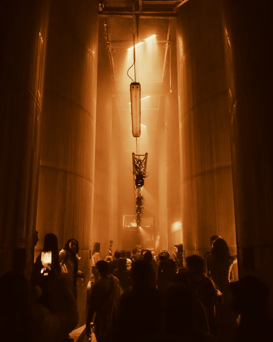 PEAK audience in an architectural interior illuminated by warm orange lighting